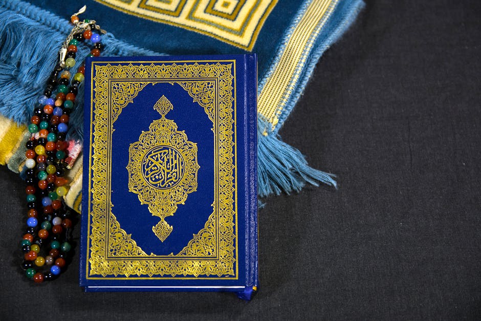 Foto sebuah naskah klasik kitab kuning bertuliskan kaligrafi Arab yang rapi di atas meja kayu tua, dikelilingi oleh tumpukan kitab-kitab teologi Islam di dalam sebuah perpustakaan tradisional yang memiliki pencahayaan temaram dan tenang.