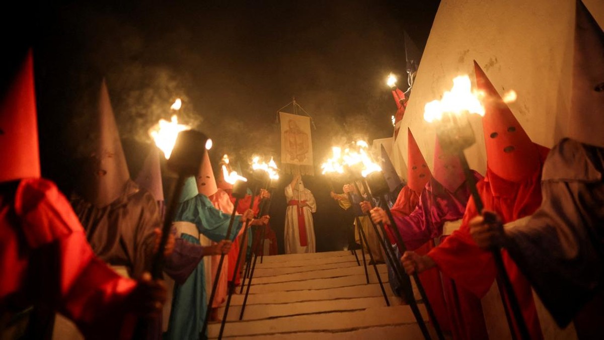 Umat Katolik berkerudung mengikuti Prosesi Fogaréu di Goiás, Brasil, Kamis (2/3/2026), tradisi Pekan Suci yang menggambarkan pengejaran dan penangkapan Yesus Kristus dalam prosesi religius tengah malam. (REUTERS/Adriano Machado)