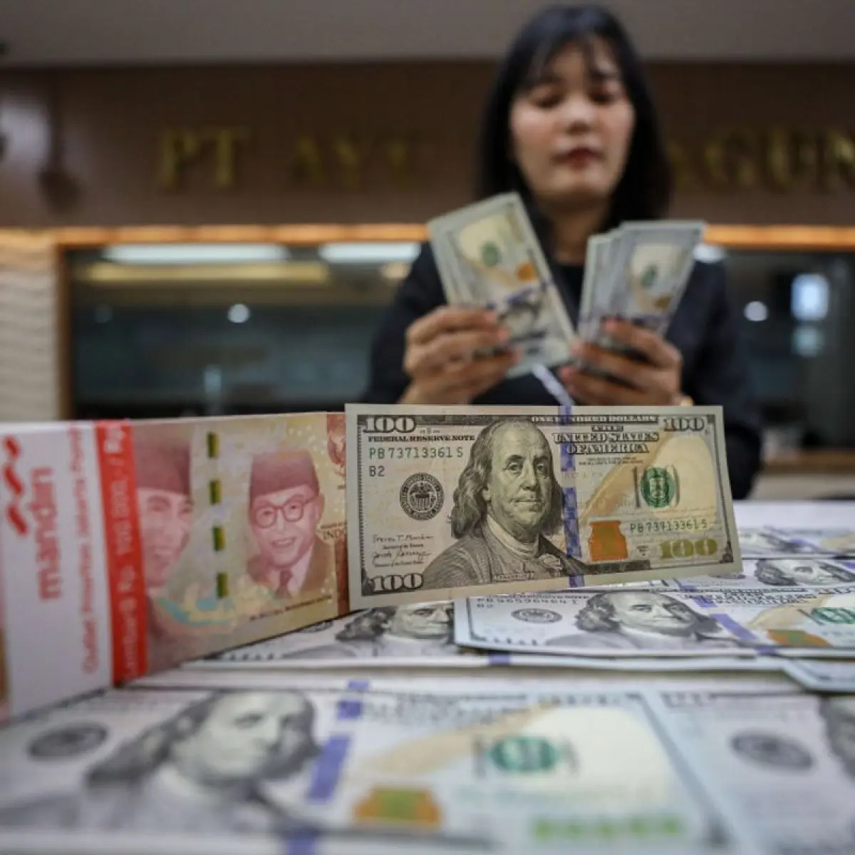 Karyawan menunjukan mata uang dolar AS dan rupiah di salah satu tempat penukaran uang di Jakarta, Senin (12/1/2026). Bisnis/Eusebio Chrysnamurti