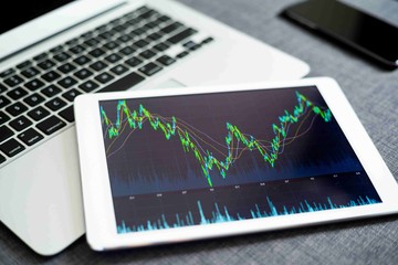 Ilustrasi grafik saham dalam latar belakang hitam pada tablet