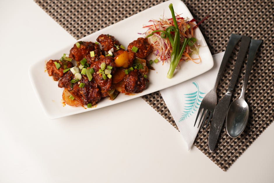 Ayam goreng berwarna cokelat keemasan yang berkilau karena balutan saus mentega kental, disajikan di piring putih dengan hiasan irisan bawang bombay dan taburan daun bawang segar.