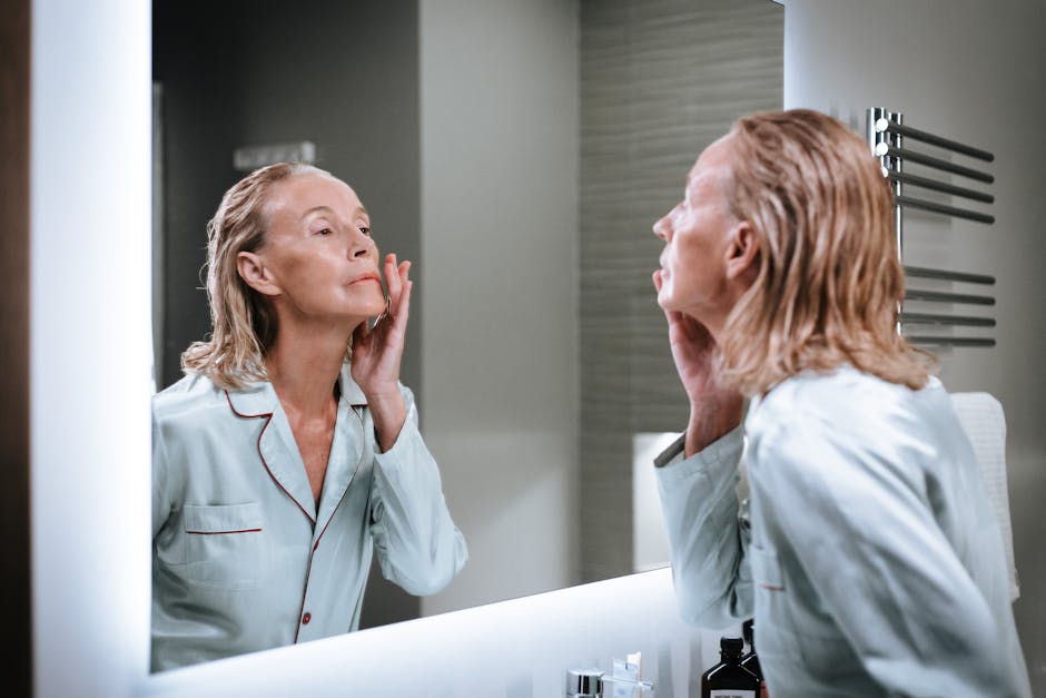 Seorang wanita tersenyum sambil mengaplikasikan tabir surya di wajahnya di bawah sinar matahari pagi.